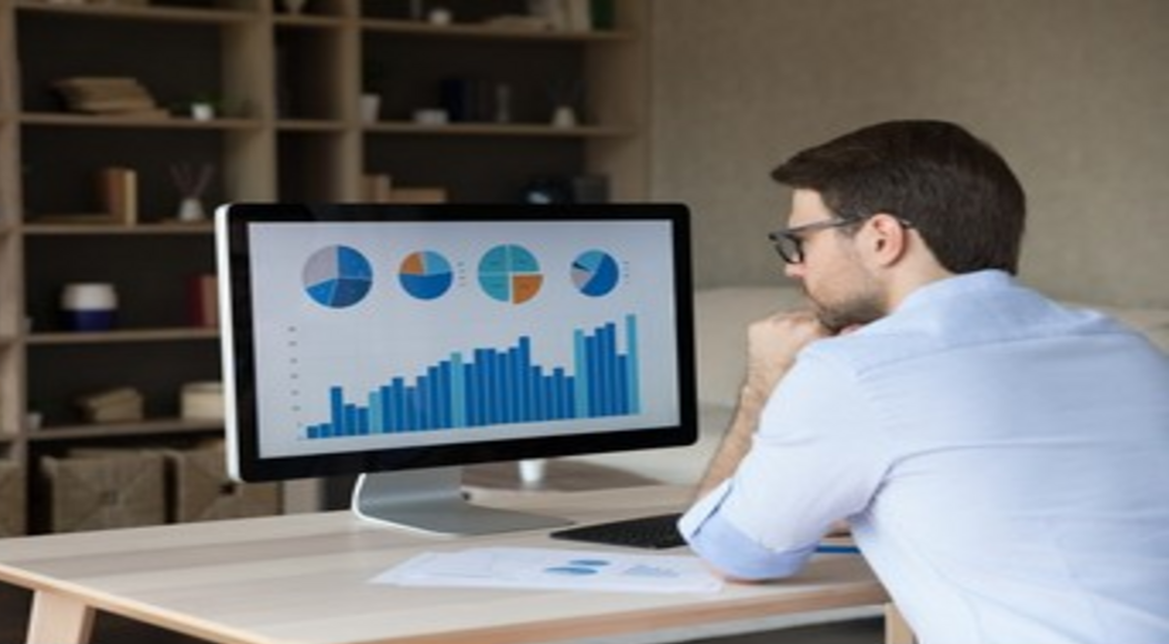 Gráficos financeiros e moedas com um smartphone exibindo "Orçamento Pessoal", representando a tecnologia simplificando o controle financeiro.